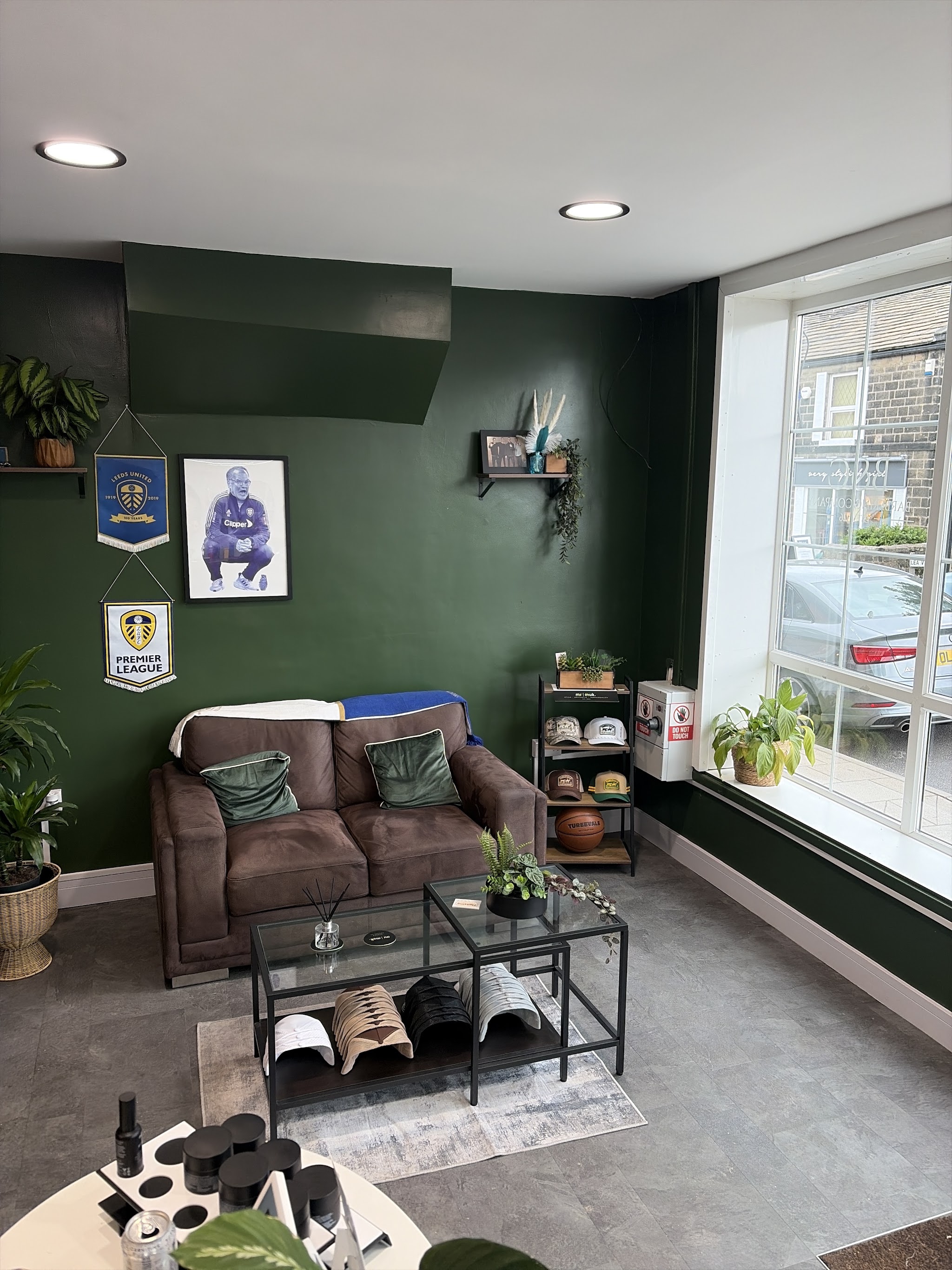 B&C's green waiting area with a brown sofa, plants and Leeds United memorabilia